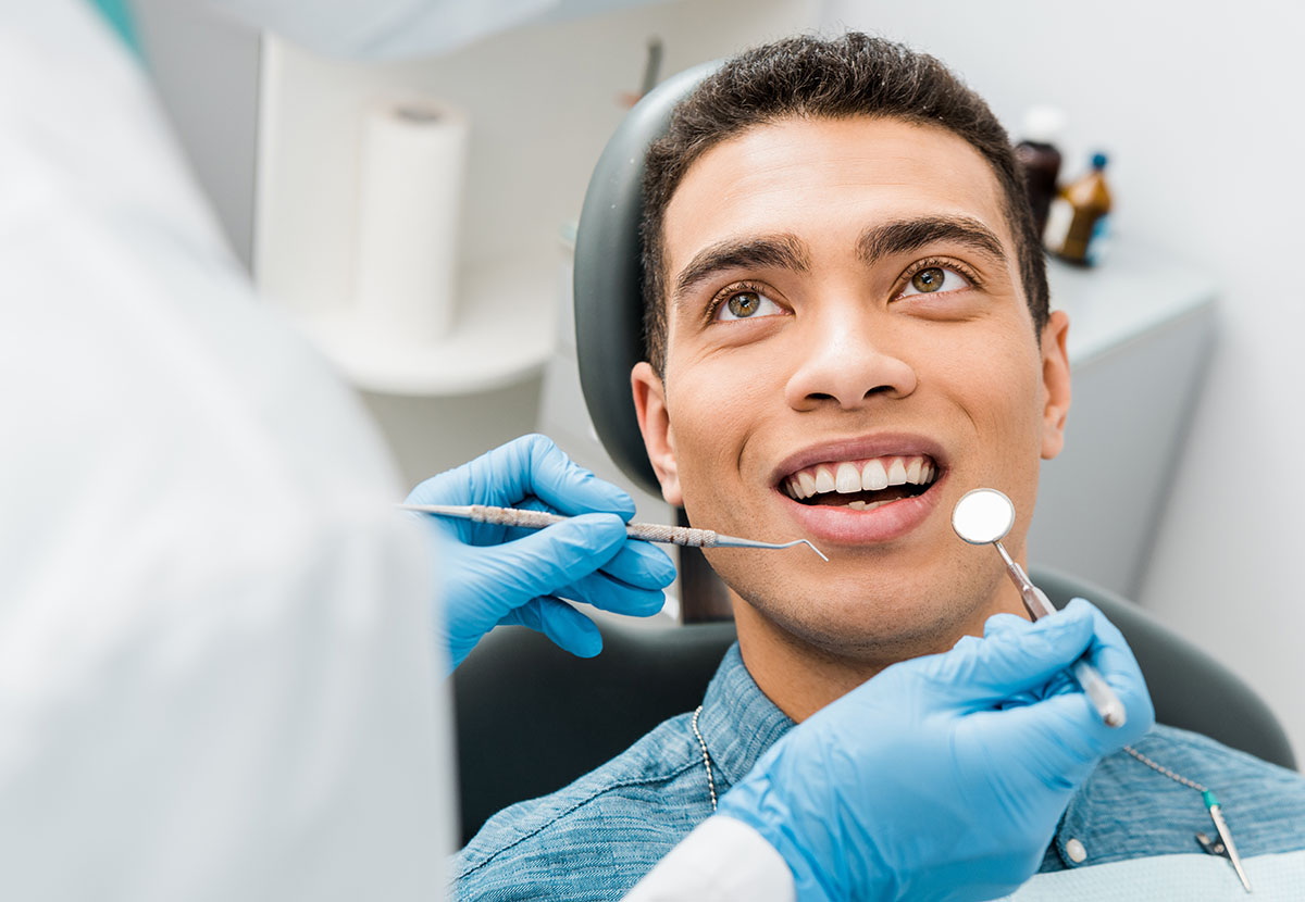 cheerful african american man with during examination in dental affordable dental care in houston tx - adonia dentistry