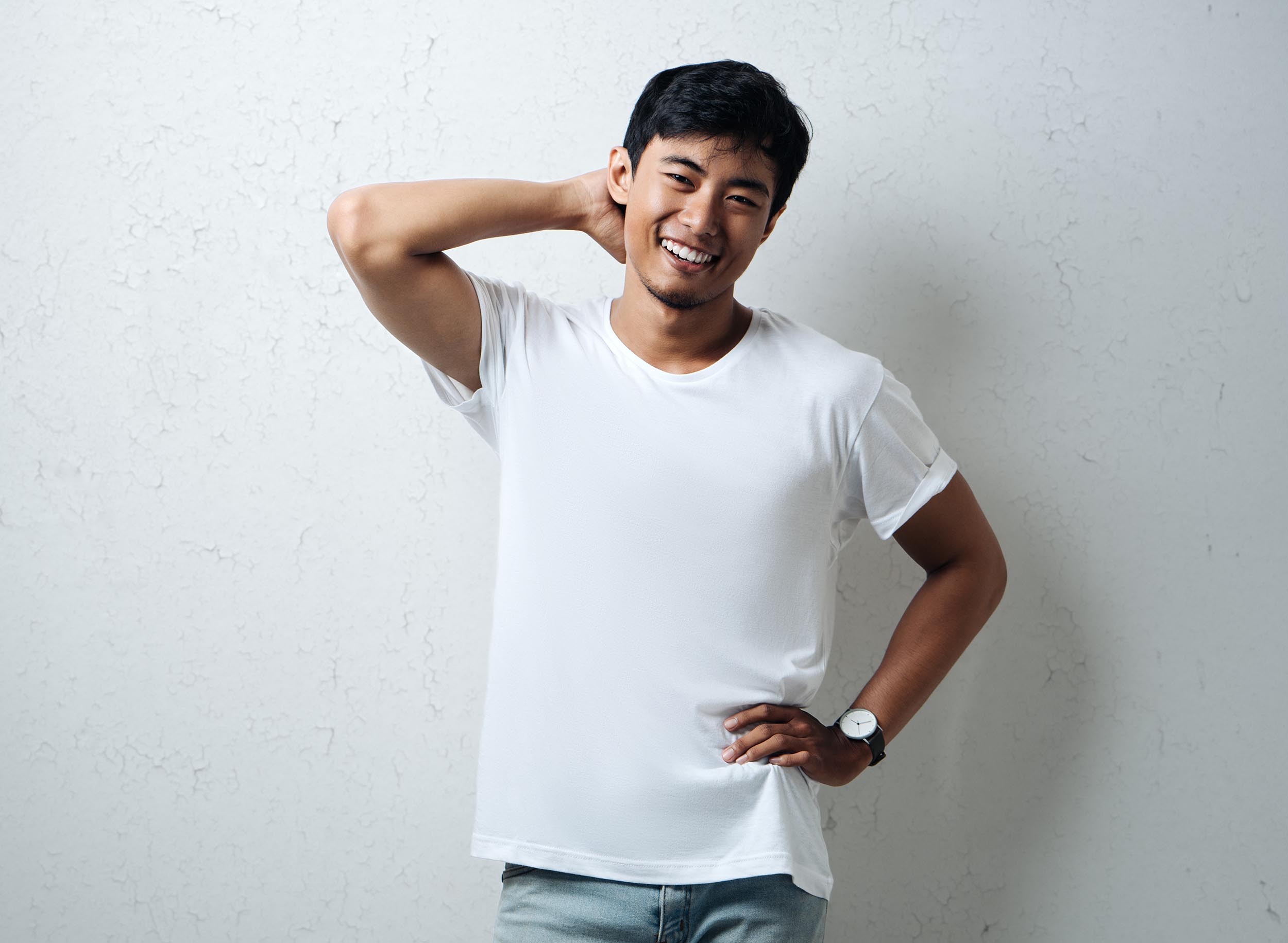 Smiling guy in white blank t-shirt, grunge wall, horizontal stud teeth whitening in houston tx - adonia dentistry